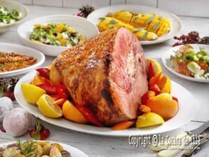 Un pavo relleno, un jamón glaseado y costillas de cerdo se exhiben en un elegante plato de Navidad.