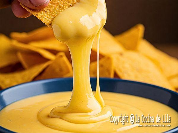 Salsa cheddar cremosa casera servida en bol con nachos o totopos.